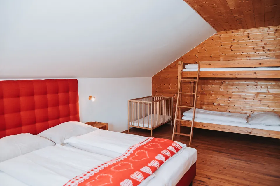 Vierbettzimmer mit Doppelbett, Stockbett und Gitterbett unter der Dachschräge