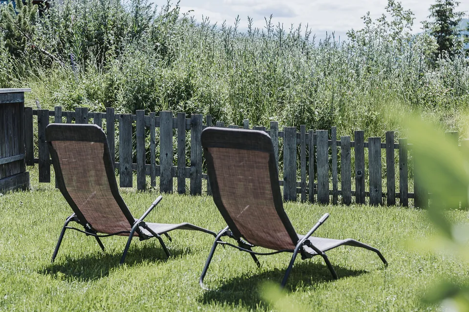 Zwei Liegestühle im eingezäunten Garten des Almchalets