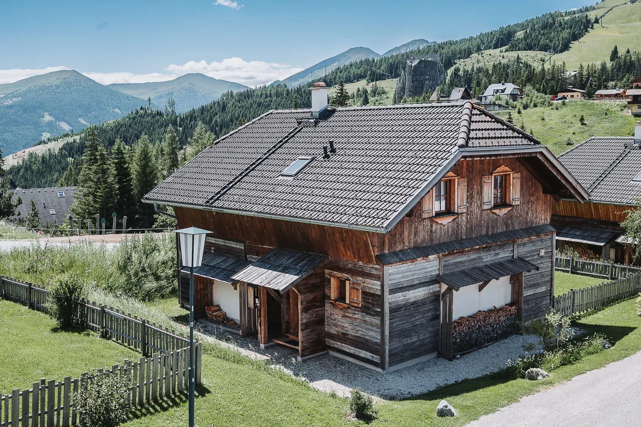 Almchalet am Katschberg im Sommer, dahinter Wiesen und Berge
