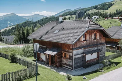 Almchalet am Katschberg im Sommer, dahinter Wiesen und Berge