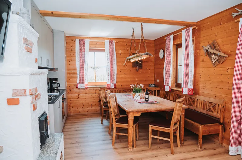 Wohnküche mit Esstisch, Eckbank und Kachelofen im Almchalet