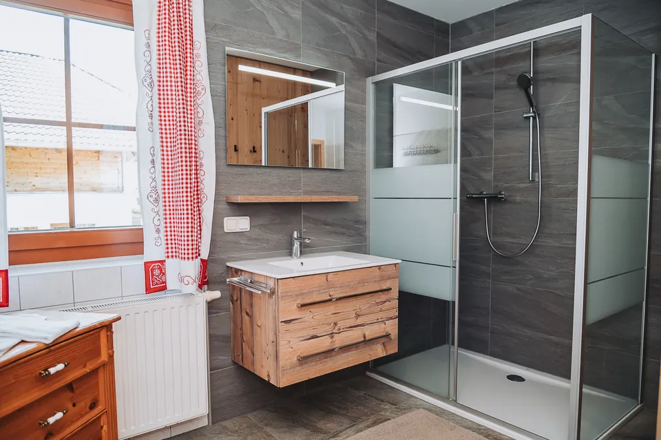 Tageslicht-Bad mit Dusche und Holzwaschtisch in der Almhütte