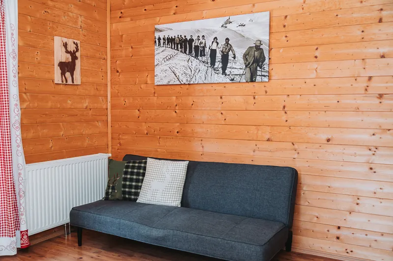 Couchecke mit grauem Sofa an der Holzwand der Almhütte