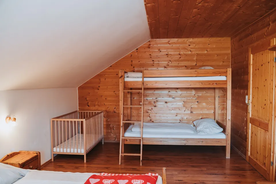 Vierbettzimmer mit Stockbett und Gitterbett unter der Dachschräge