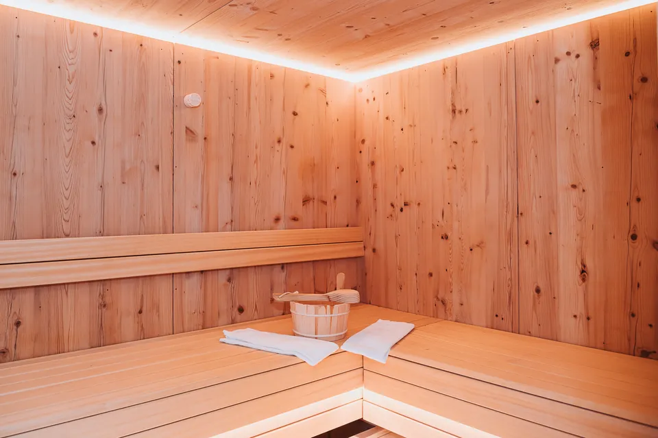Sauna aus hellem Holz mit Saunakübel und Handtuch