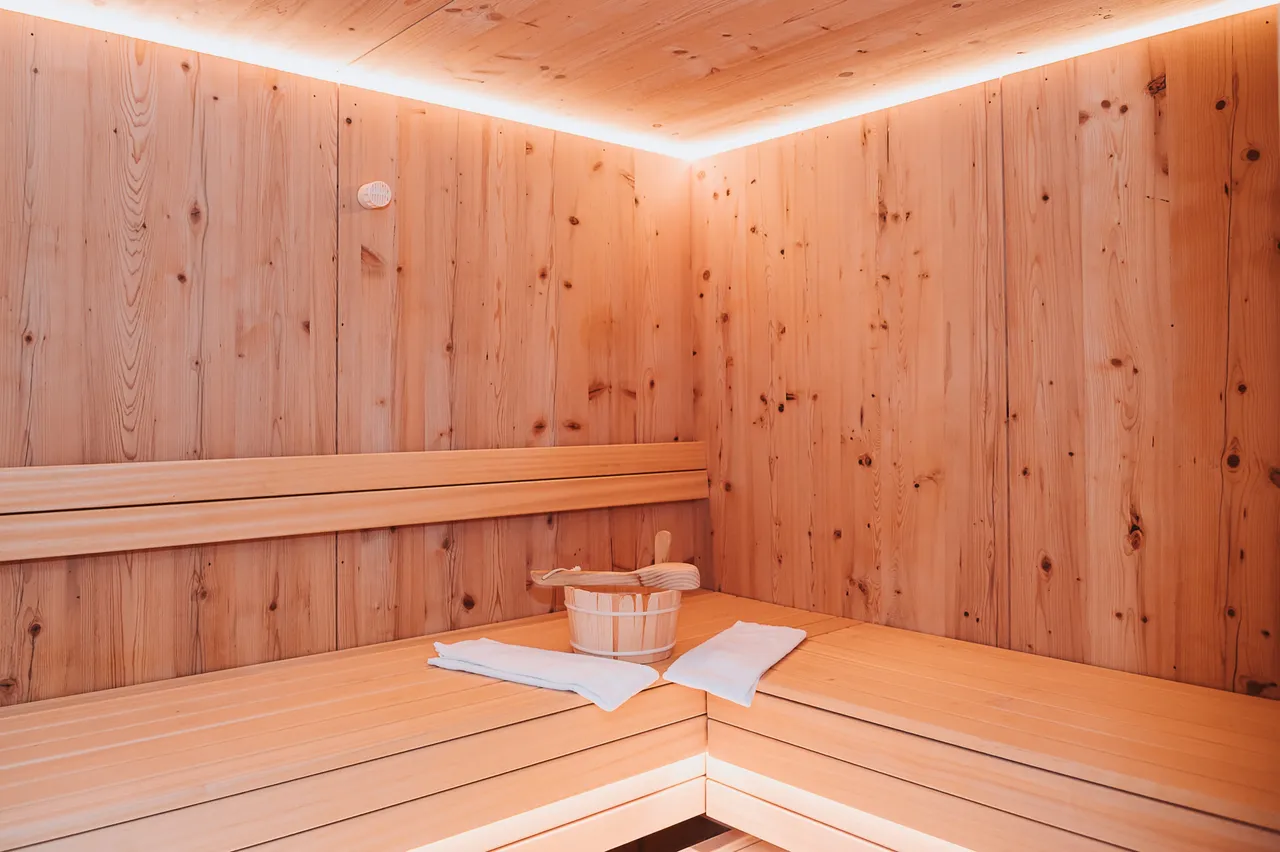 Sauna aus hellem Holz mit Saunakübel und Handtuch