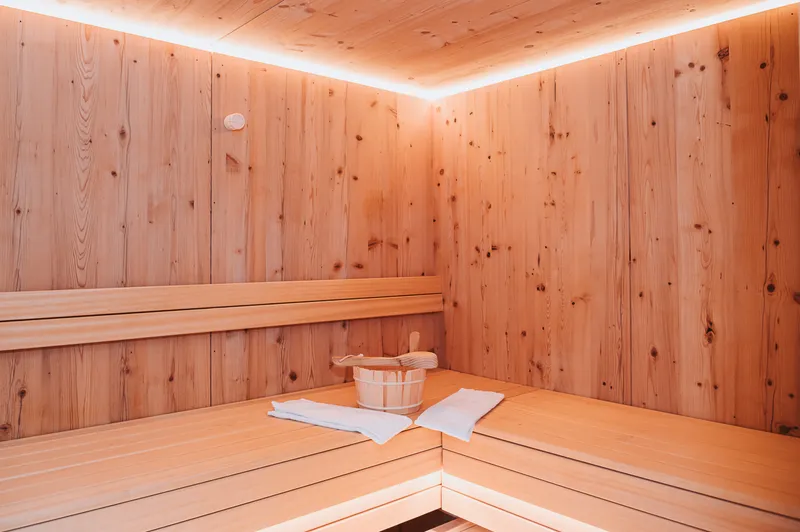 Sauna aus hellem Holz mit Saunakübel und Handtuch
