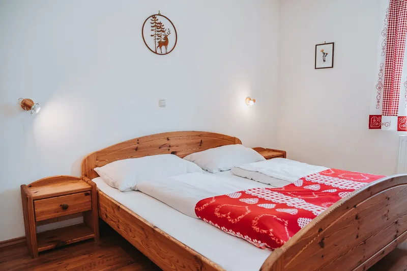 Doppelbett aus Holz mit rot-weißer Decke im Schlafzimmer im Erdgeschoss