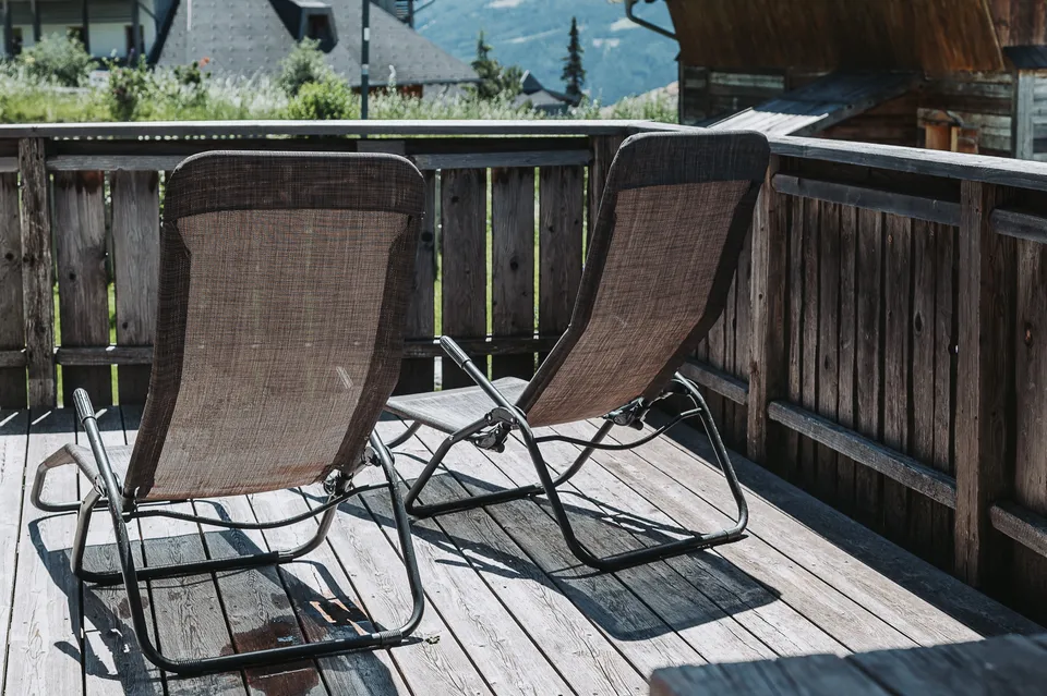 Zwei Liegestühle auf der Holzterrasse der Almhütte