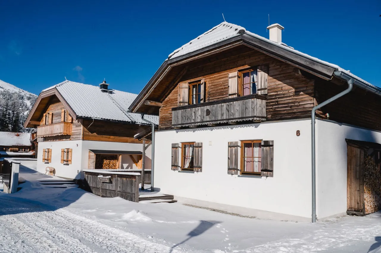 Zwei verschneite Almhütten mit Holzbalkon im Almdorf Katschberg
