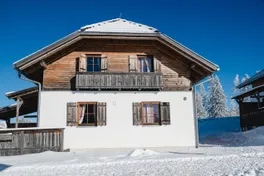Almhütte mit Holzbalkon und Fensterläden im Winter