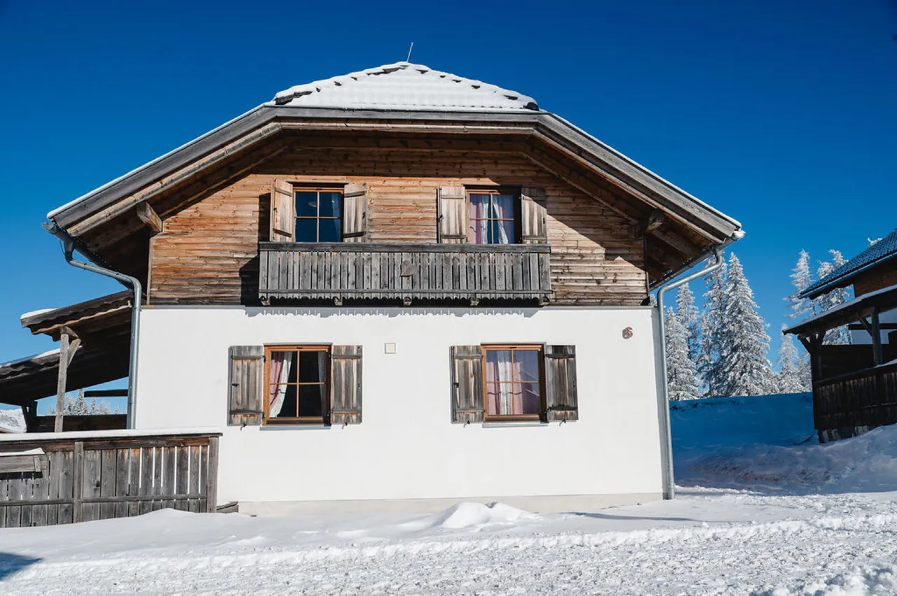 Almhütte mit Holzbalkon und Fensterläden im Winter