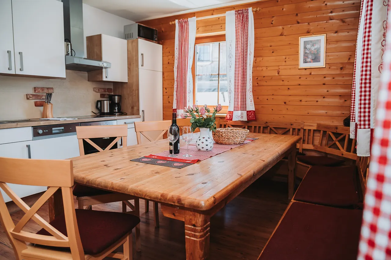 Wohnküche der Almhütte mit großem Holztisch und Eckbank