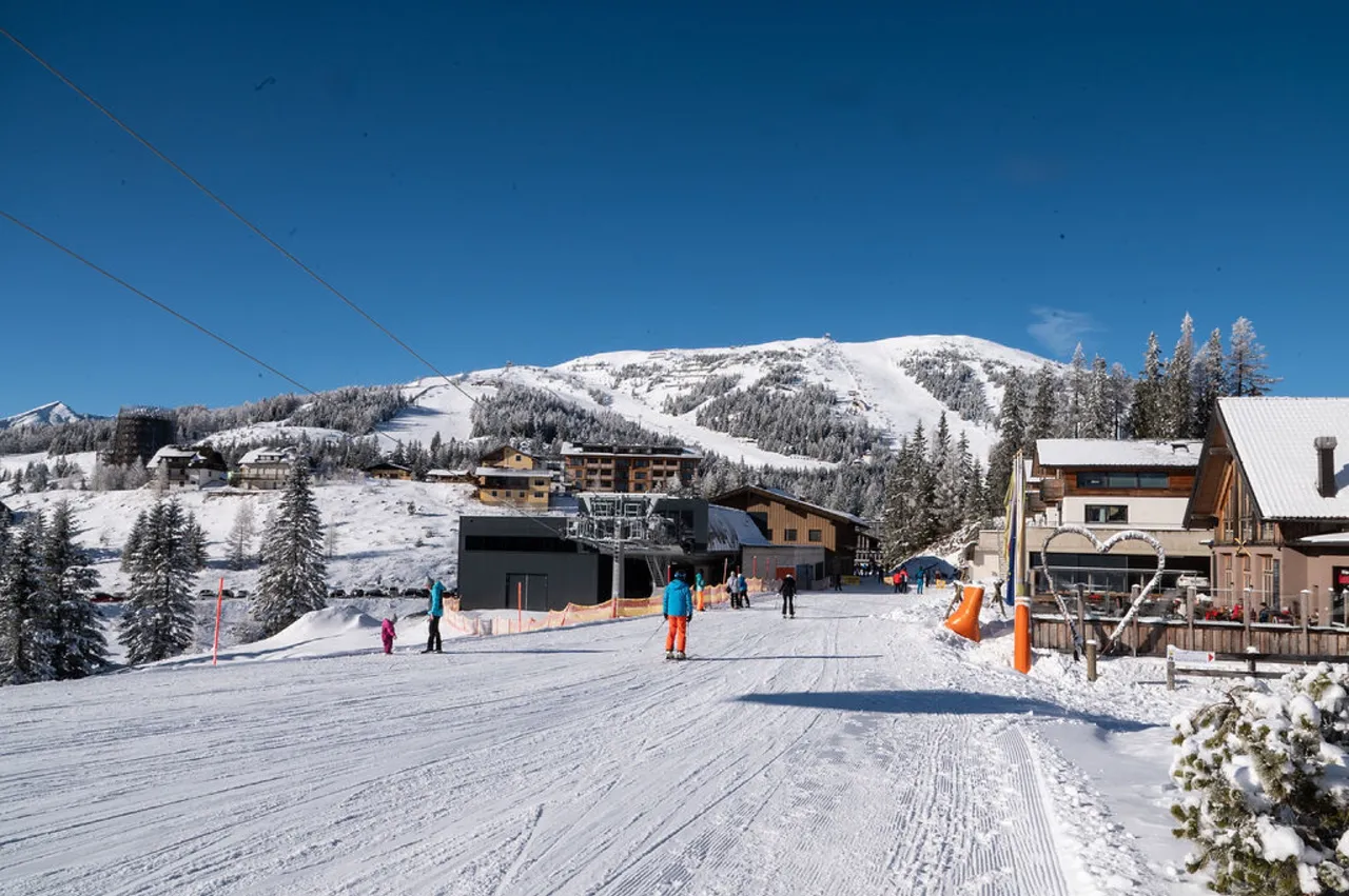 Skipiste mitten im Ort Katschberg mit Skifahrern und Liften