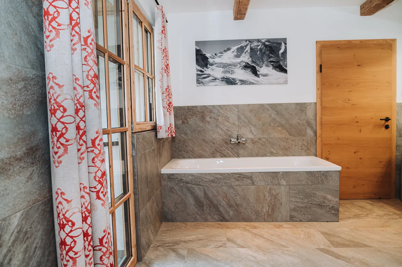 Badezimmer mit Badewanne und Steinfliesen im Chalet Panorama