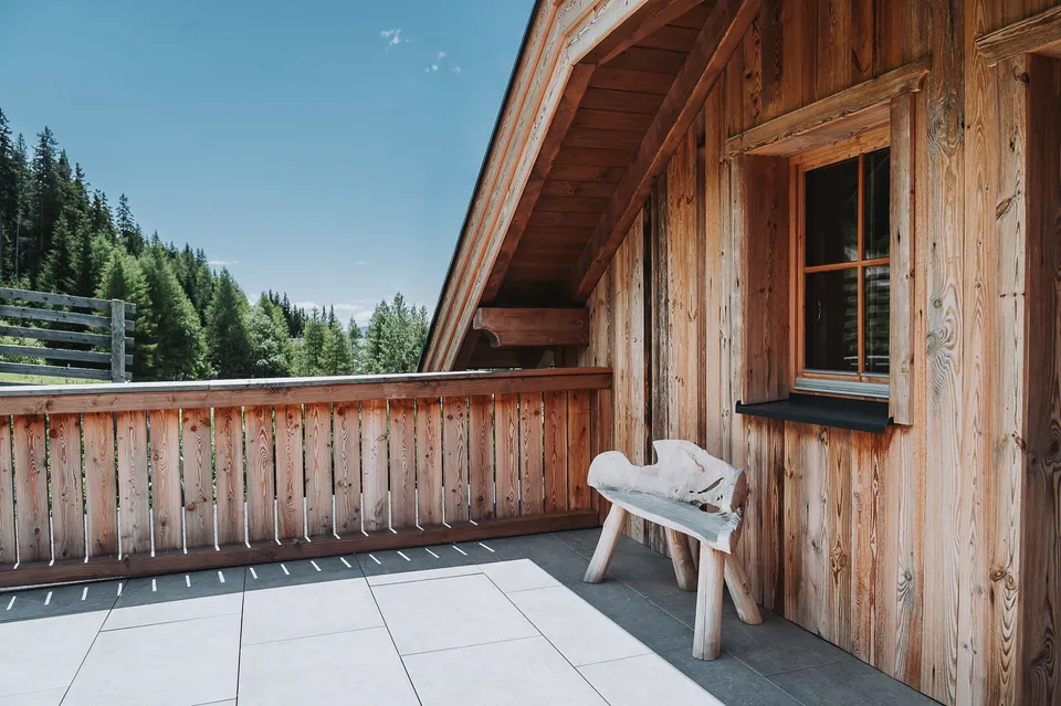 Holzbalkon mit Bank und Blick auf den Wald