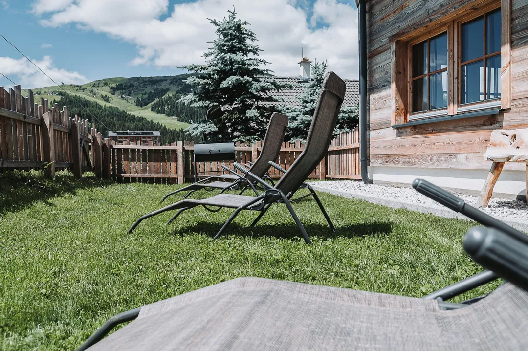 Liegestühle auf der Wiese vor dem Chalet Panorama mit Blick auf die Hänge