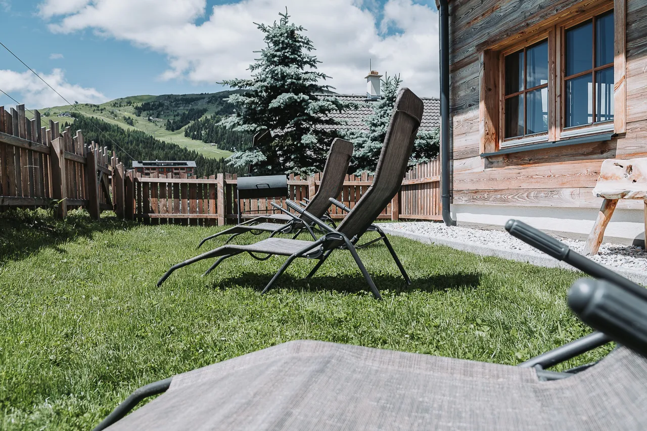 Liegestühle auf der Wiese vor dem Chalet Panorama mit Blick auf die Hänge