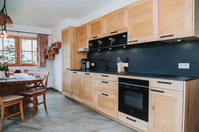 Moderne Küche mit Holzfronten, Backofen und dunkler Arbeitsplatte
