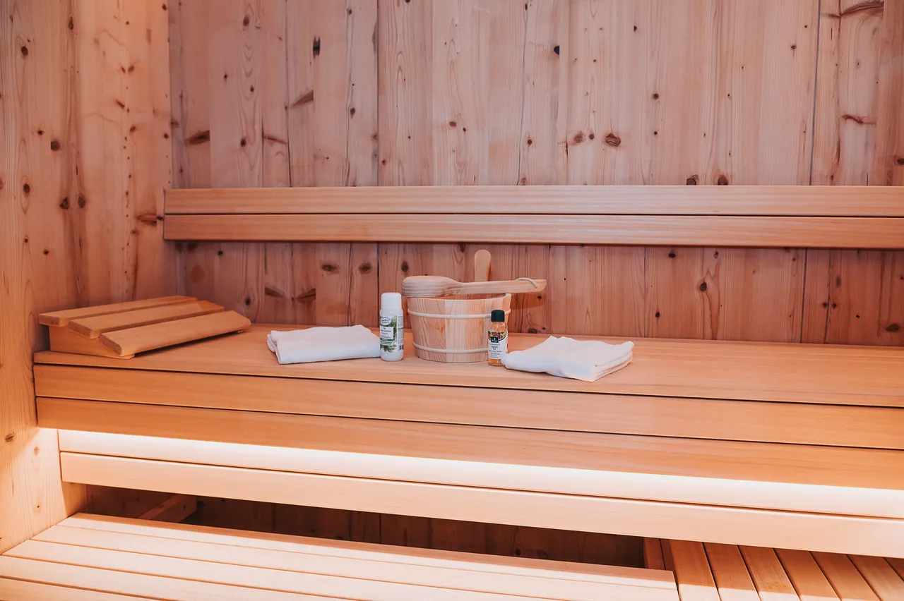 Private Sauna aus hellem Holz mit Handtüchern und Saunakübel