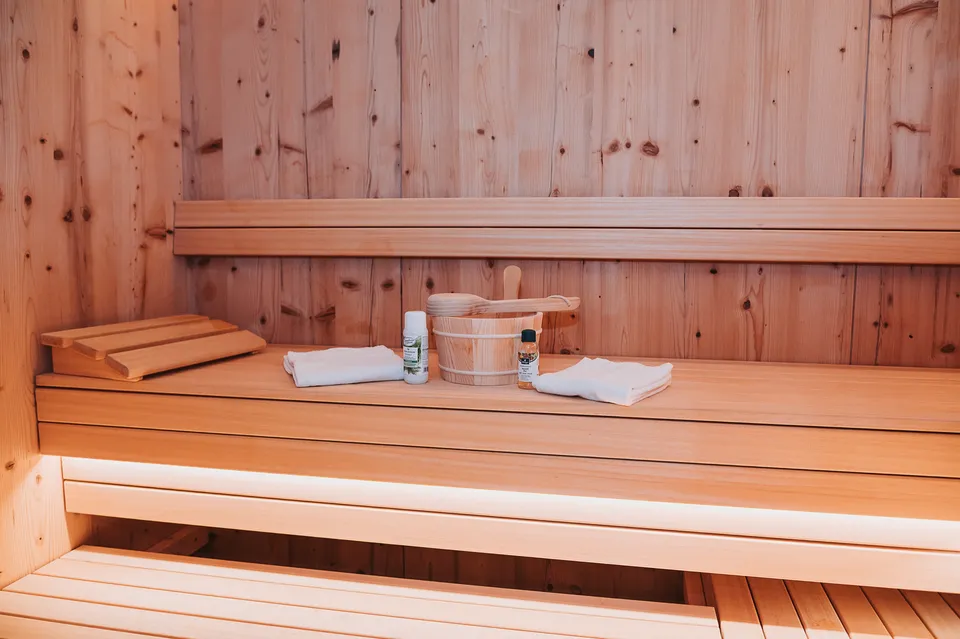 Private Sauna aus hellem Holz mit Handtüchern und Saunakübel