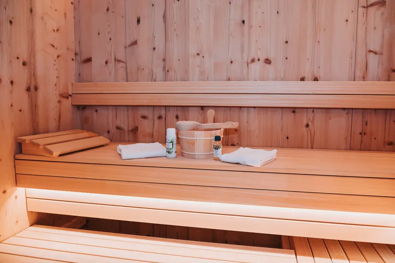 Private Sauna aus hellem Holz mit Handtüchern und Saunakübel