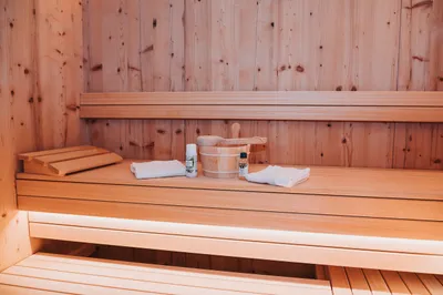 Private Sauna aus hellem Holz mit Handtüchern und Saunakübel