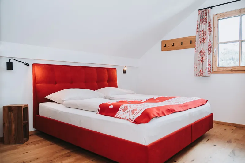 Doppelbett mit rotem Polsterrahmen unter der Dachschräge
