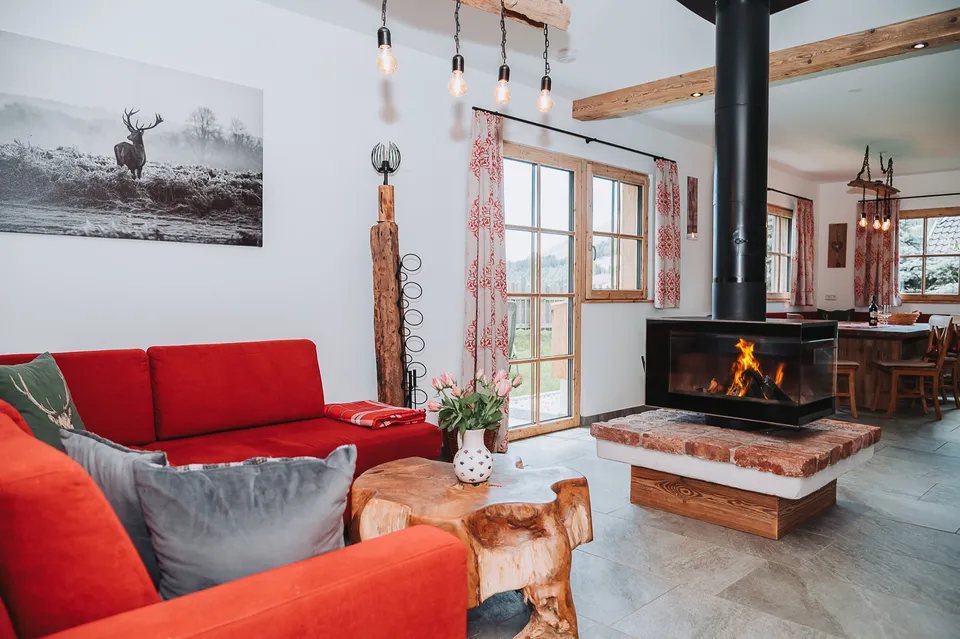 Wohnbereich mit rotem Ecksofa und Schwebekamin im Chalet Panorama