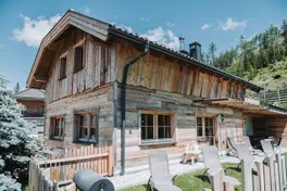 Chalet Panorama mit Holzzaun und Liegestühlen im Sommer