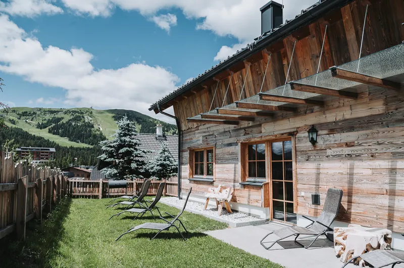 Terrasse mit Liegestühlen vor dem Chalet Panorama, dahinter grüne Hänge