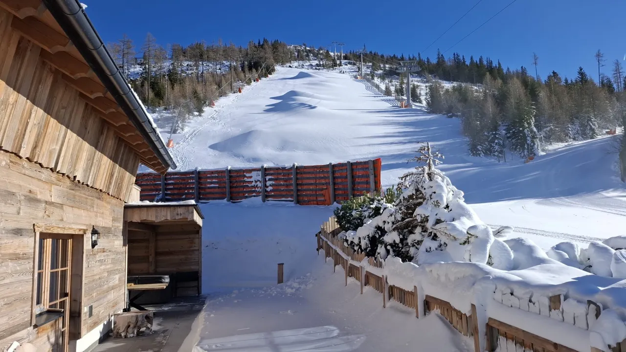 Verschneiter Weg am Chalet Panorama mit Blick auf die Piste