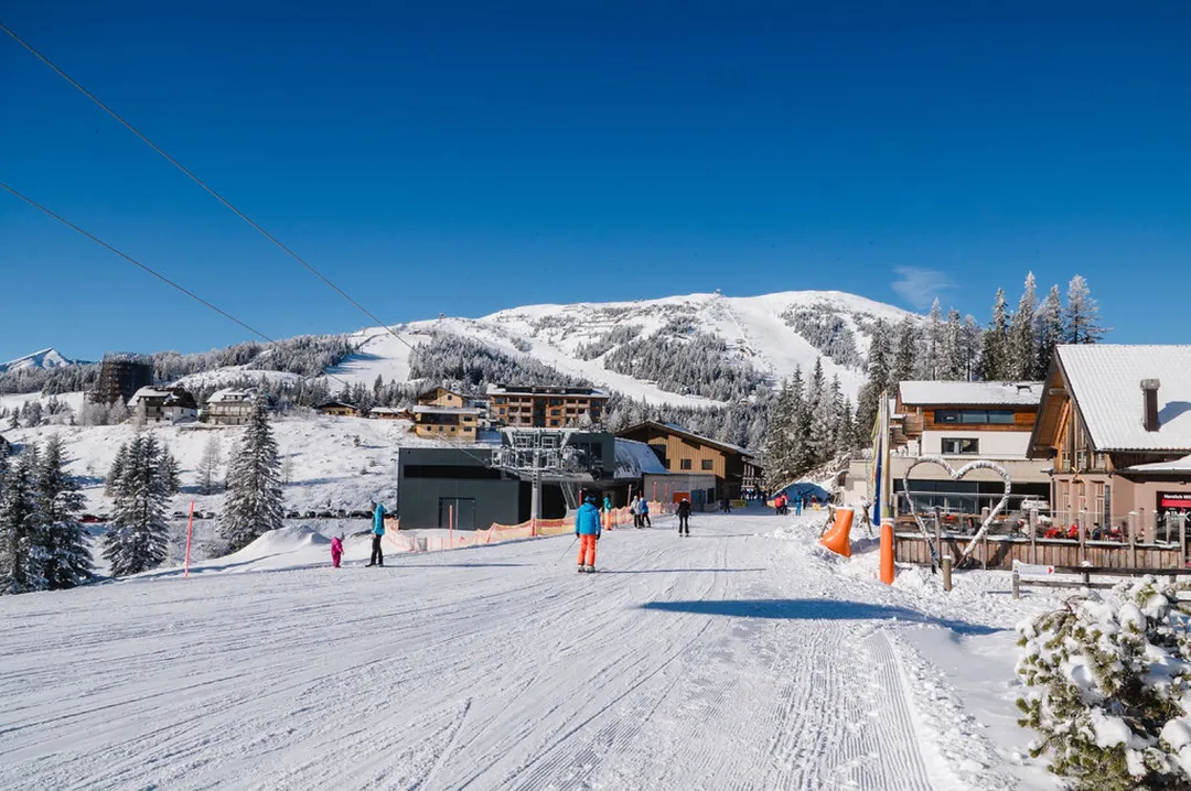Skipiste am Katschberg mit Liftstation und verschneiten Bergen